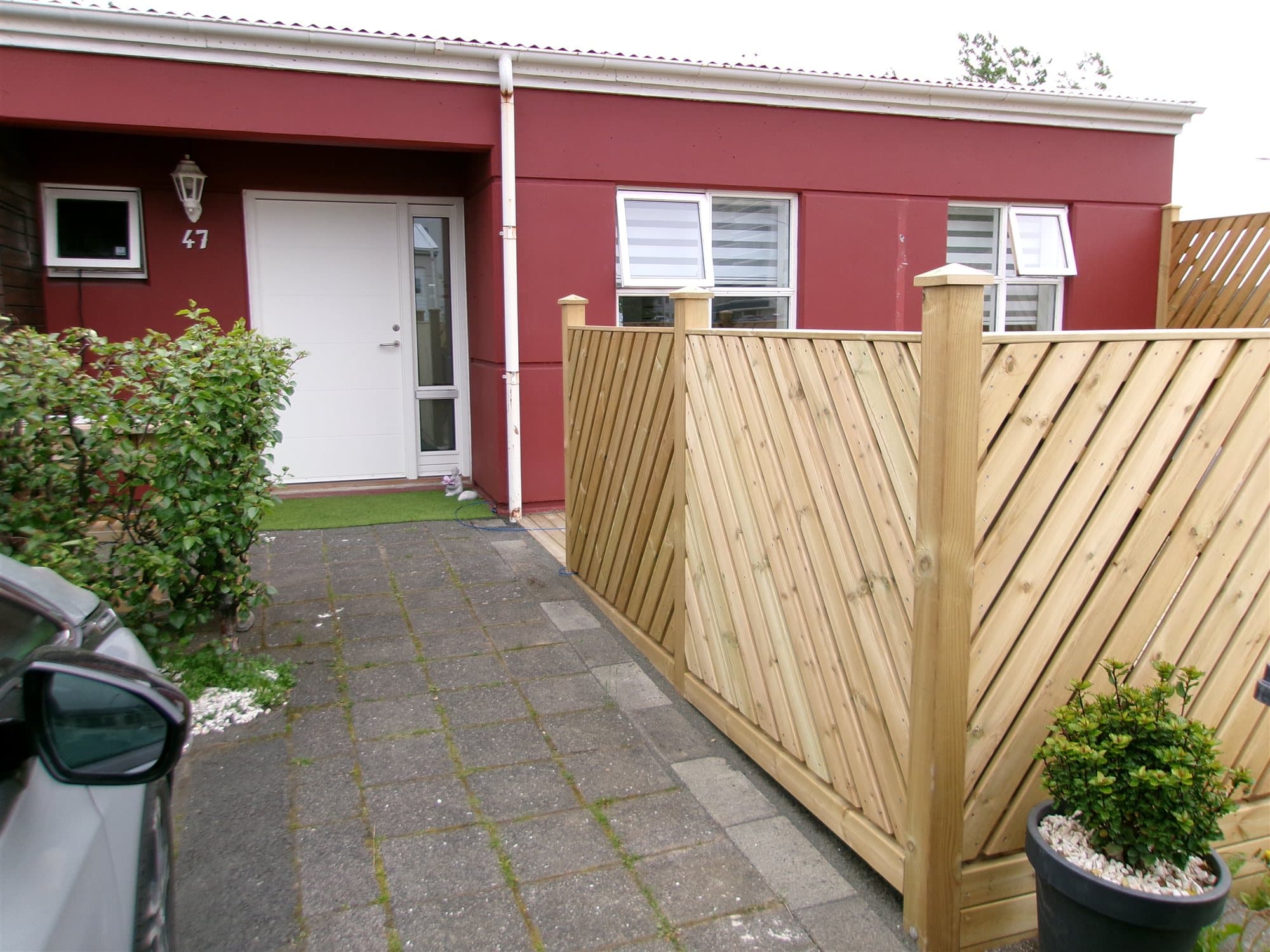 Skjólveggur og hellulögð stétt við inngang í Krummahólum